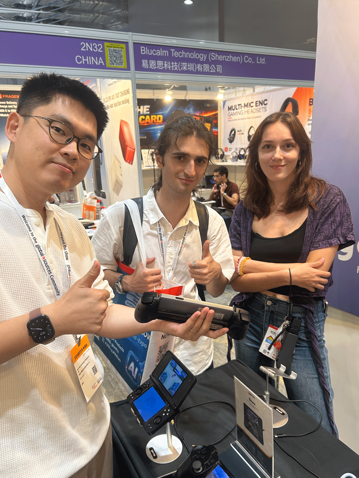 Visitors posing with Yoniq gaming hardware at the booth